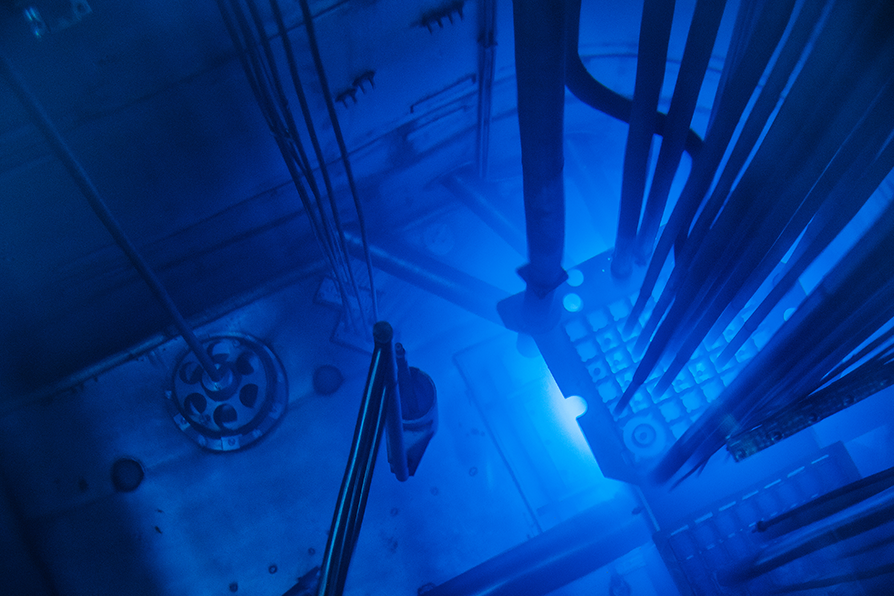 Blue-lit reactor pool inside a nuclear facility